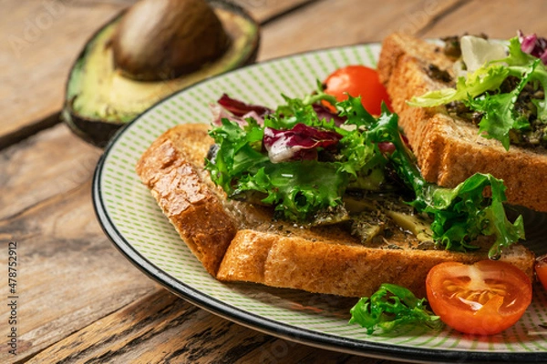 Obraz toast with avocado. vegetarian breakfast. Vegan or Vegetarian Toast with mashed avocado, arugula served on wooden board