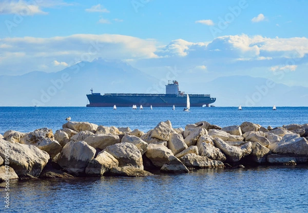 Fototapeta Stone pier, big cargo ship and many small optimist-class sailboats in the Gulf of Naples