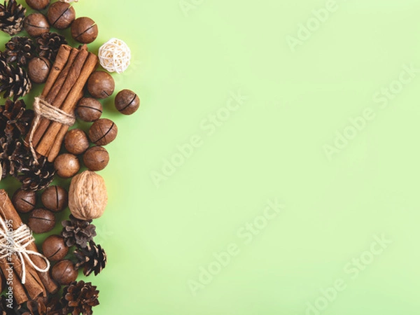 Fototapeta Christmas or New Year natural composition of nuts and cones in the form on the green background. Beige and green natural design.