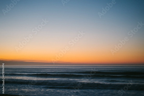 Fototapeta Small waves approaching the shore of Ilbarritz beach during a winter sunset