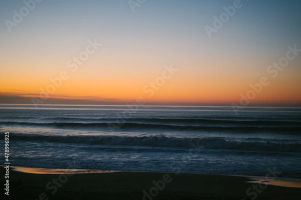Fototapeta Small waves approaching the shore of Ilbarritz beach during a winter sunset