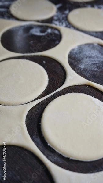 Obraz cooking process, modeling, recipe, dough, cut out round pieces, roll out with a wooden rolling pin, flour, dumplings