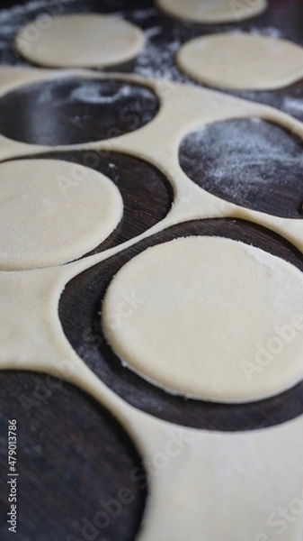 Obraz cooking process, modeling, recipe, dough, cut out round pieces, roll out with a wooden rolling pin, flour, dumplings