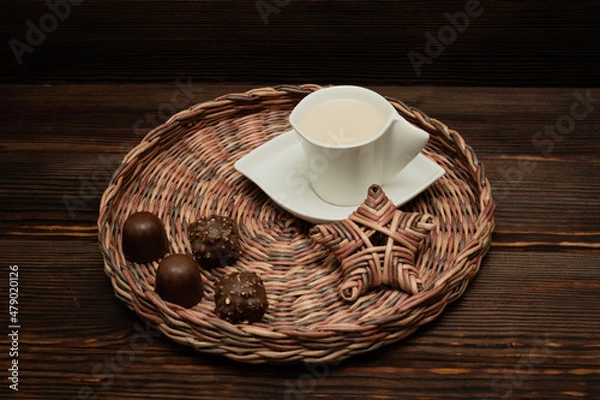 Obraz A cup of tea on a wicker tray. Chocolates.