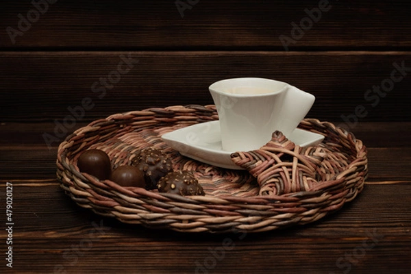 Obraz A cup of tea on a wicker tray. Chocolates.