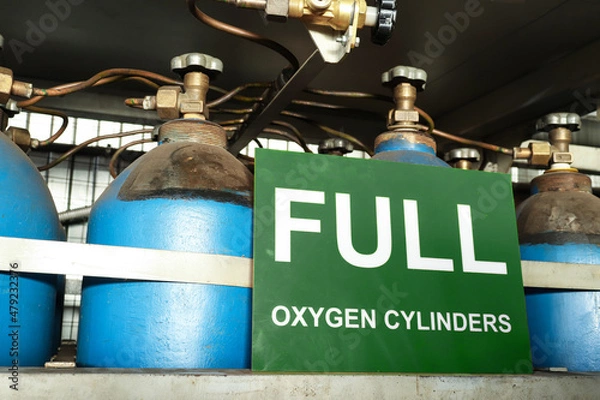 Fototapeta Green signboard notifying about full oxygen cylinders behind a stack of empty cylinders