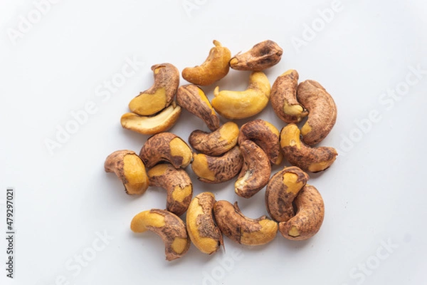 Fototapeta Close up of roasted cashew nuts with skin on white background. Cashew nuts salted with peel- rich in protein, antioxidants, and fiber.