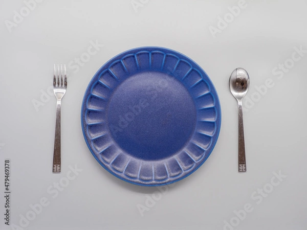 Obraz 白い背景に置かれた紺色のお皿とカトラリー（フォーク及びスプーン）
