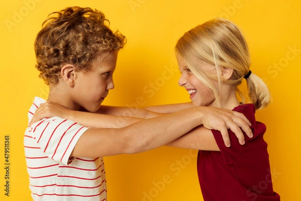 Fototapeta Boy and girl cuddling fashion childhood entertainment yellow background
