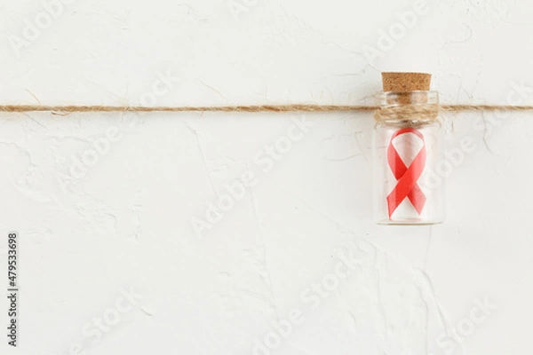 Fototapeta Glass bottle with a red ribbon inside.