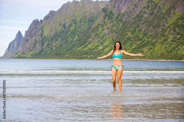 Fototapeta Woman, enjoying freezing cold water in Ersfjord Beach on Senja island, beautiful landscape view over mountains
