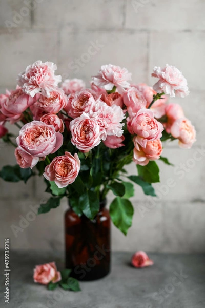 Fototapeta A beautiful bouquet of carnations and pink-cream peony roses in a dark vase. Interior decoration with flower arrangements.