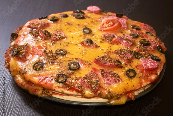Fototapeta Three-layer homemade pizza with cheese, sausages, ham and olives. Close-up, selective focus.