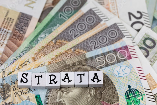 Fototapeta The wording "Strata" translated as "Loss" plus many Polish banknotes. Increasing costs of business activity. Photo taken under artificial, soft light