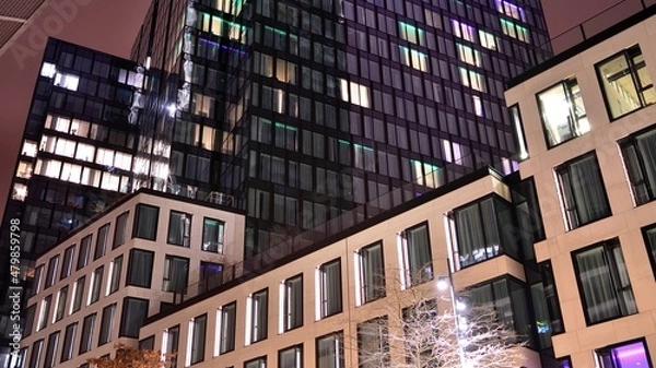 Fototapeta Office building at night, building facade with glass and lights. View with illuminated modern skyscraper.