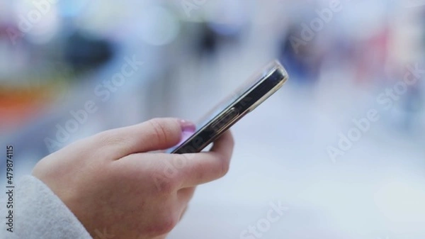 Fototapeta Hand of Young Caucasian Woman Using Smartphone Swiping on Screen Browsing Internet for Information	