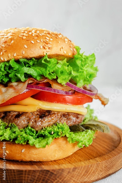 Fototapeta Close up of homemade burger on wooden plate. Fast food concept.