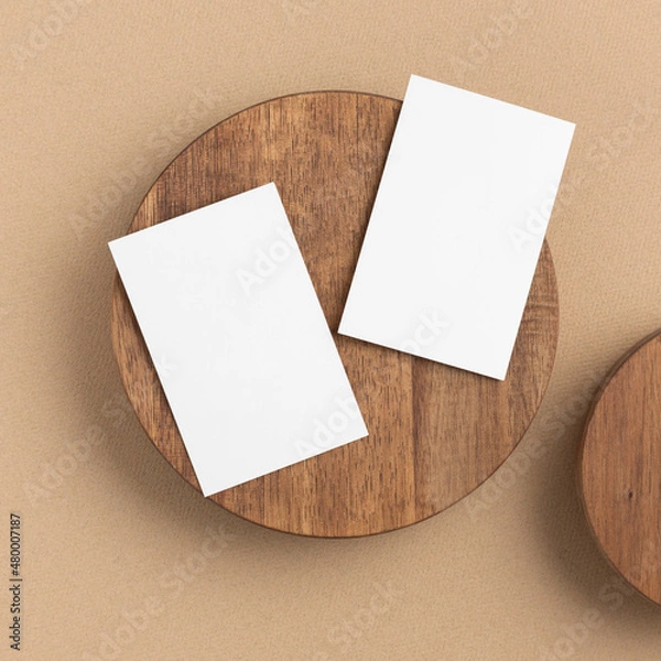 Obraz Business cards on a wooden round plate on a beige background - top view, closeup.