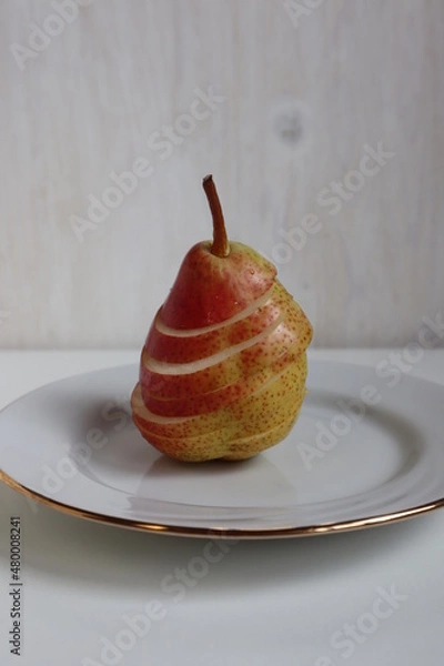 Fototapeta Red pear cut into circles, on a white plate.	