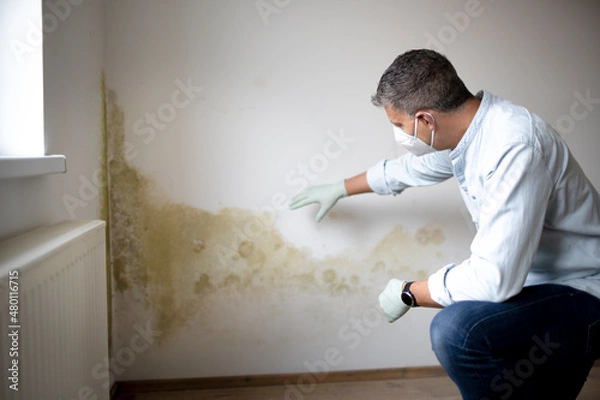 Obraz Man with mouth nose mask and blue shirt and gloves n front of white wall with mold