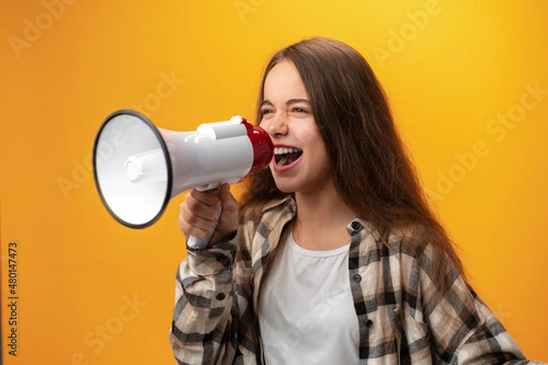 Fototapeta Child girl using megaphone against yellow background