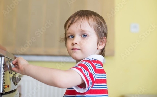 Fototapeta Little baby boy is touching cooker - danger in home