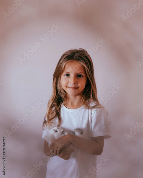 Fototapeta Close-up portrait of beautiful blond toddler girl hugging her favorite handmade toy, knitted cat.