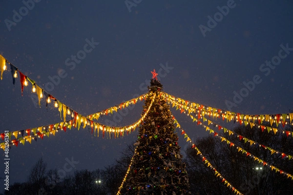 Obraz Christmas tree, colored flags and lights in the evening