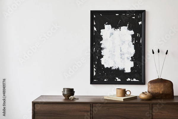 Fototapeta Creative composition of modern living room interior design with mock up poster frame, brown commode, vases and personal accessories. White wall. Copy space. Template..