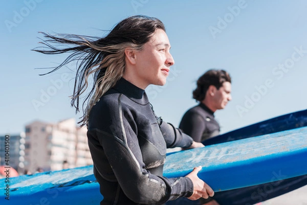 Fototapeta two latin surfers walking into the ocean to surf the waves, close up, in La Serena