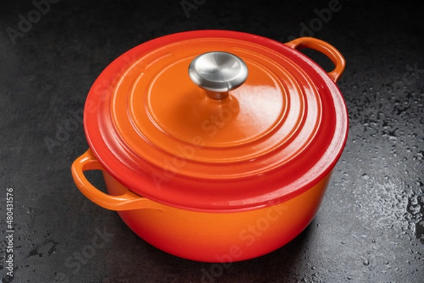 Obraz orange dutch oven on wet black surface.