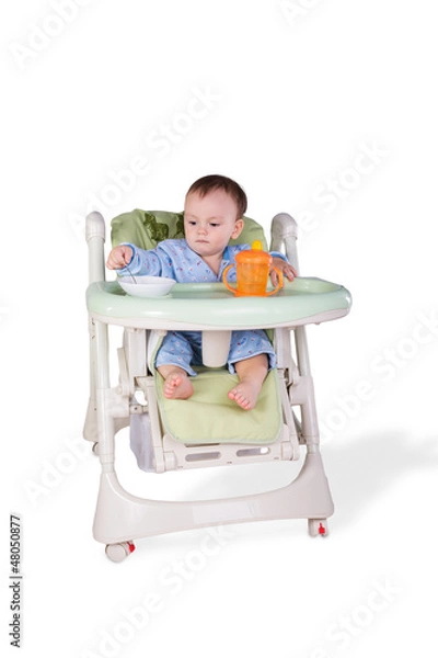 Obraz child is eating sitting at table, isolated over white