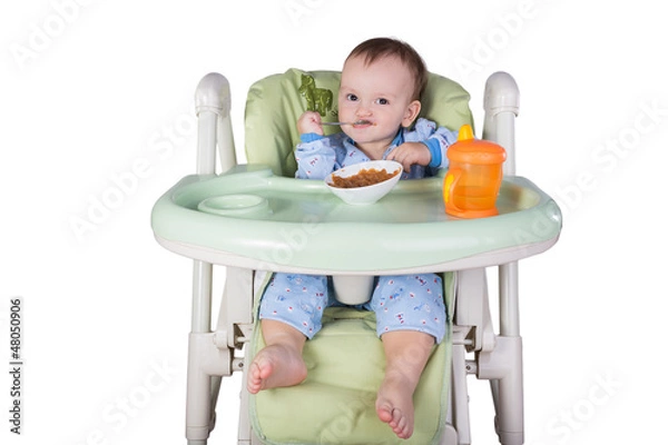 Obraz child is eating sitting at table, isolated over white