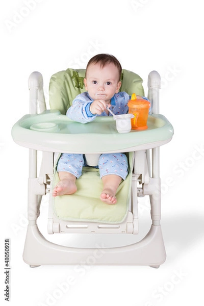 Obraz child is eating sitting at table, isolated over white