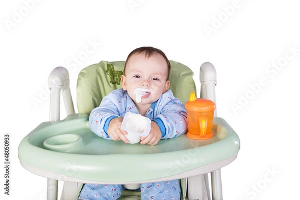 Obraz child is eating sitting at table, isolated over white