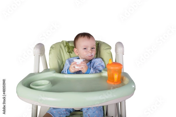 Obraz child is eating sitting at table, isolated over white