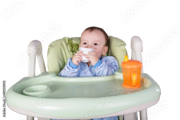Obraz child is eating sitting at table, isolated over white