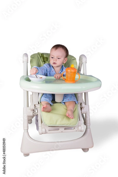 Obraz child is eating sitting at table, isolated over white