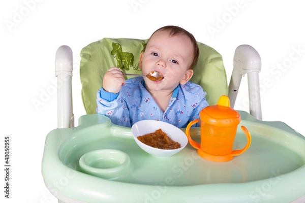 Obraz child is eating sitting at table, isolated over white