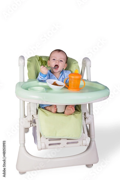 Obraz child is eating sitting at table, isolated over white