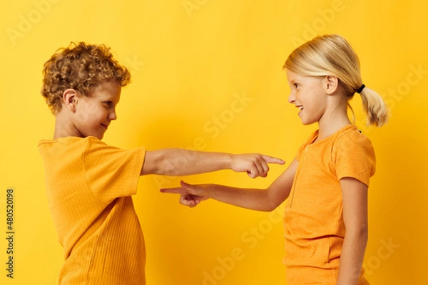 Fototapeta cheerful children in yellow t-shirts standing side by side childhood emotions yellow background unaltered