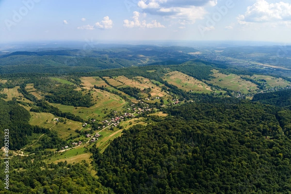 Fototapeta Aerial view of mountain hills covered with dense green lush woods on bright summer day