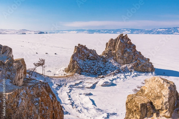 Fototapeta Sacred Shamanka Mountain on Olkhon Island in winter. View of the frozen Lake Baikal on a sunny day. View from above. Below, tourists walk on the ice