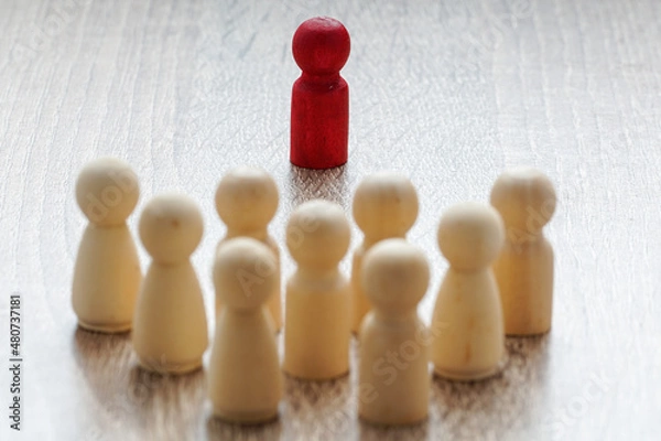 Fototapeta leadership concept. red wooden dolls standing in front of others. backlight setup on purpose