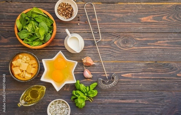 Obraz Prepared ingredients for cooking fritata or omelet on a dark wooden background. Spinach recipes.