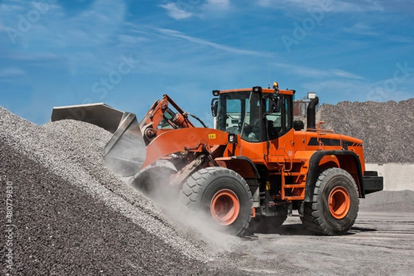 Obraz Latem pomarańczowa ładowarka ładuje kruszywo 