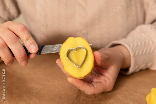 Obraz heart shaped potato stamp on craft paper. The process of decorating a gift for Valentine's Day. Getting ready for the celebration on February 14th.