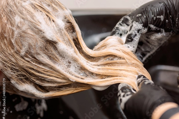 Obraz close-up. hairdresser in black rubber gloves washes hair to a client after dyeing