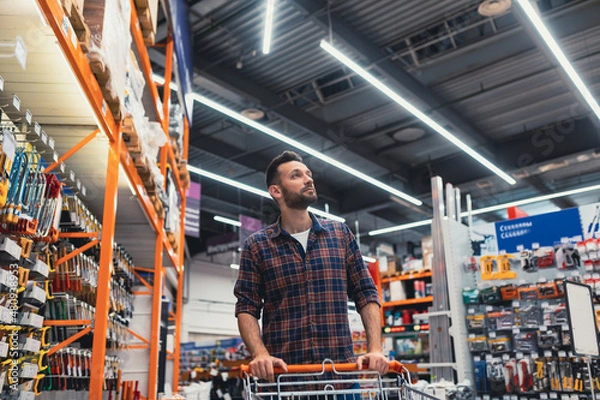 Obraz buy a man walking with a basket in a hardware store