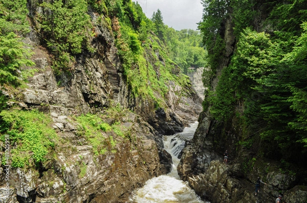 Fototapeta Waterfall in the forest crashing down between the rocks people rock climbing